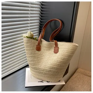 Gros plan sur la texture du sac cabas en paille avec anses en cuir marron
