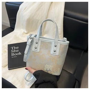 Detail of light blue bucket bag with gold embroidery on black leather sofa