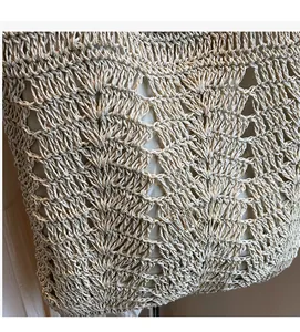 Detailed view of intricate openwork weave and shell pattern on ivory straw handbag