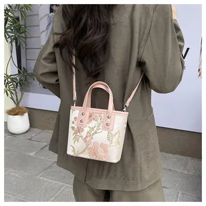 Detail of floral embroidery and pink leather strap on a Chinese style bucket bag