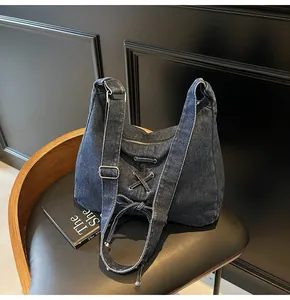 Détail du sac bandoulière en jean bleu foncé avec laçage et boucle argentée réglable