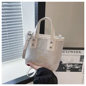 Detail of floral embroidery and silver studs on a beige Chinese-style crossbody bucket bag