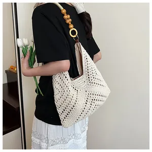 Detail of hand-woven tote bag showing hollow patterns and beaded wooden ring handle