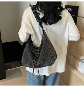 Vue arrière d'un mannequin portant un sac hobo en denim gris foncé avec nœud de serrage