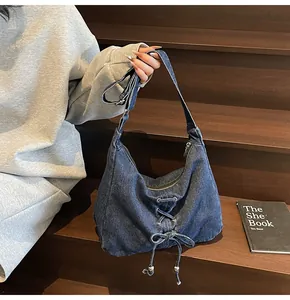 Gros plan d'un sac bandoulière en jean avec œillets métalliques et nœud papillon