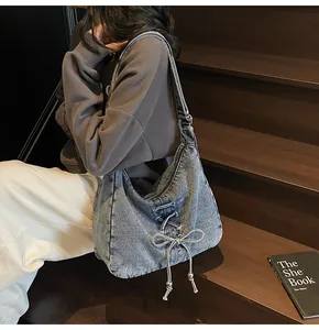 Vue style de vie d'un grand sac bandoulière en denim avec nœud décoratif sur escalier