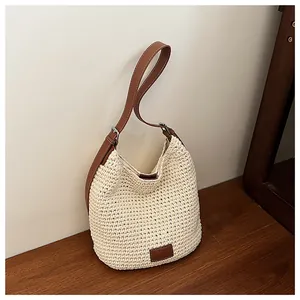 Detailopname van gehaakte shopper met leren riem en logopatch aan de onderkant