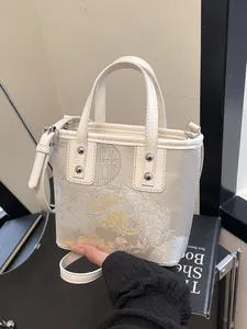 Elegant beige embroidered crossbody bucket bag with floral patterns and silver rivets