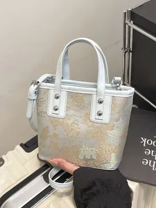 Light blue Chinese style bucket bag with gold floral embroidery and silver studs