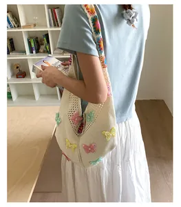 Detailansicht einer gehäkelten Umhängetasche mit Schmetterlingsmotiven und Blumenband