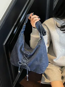 Sac bandoulière en denim bleu avec détails de lacets et accents argentés stylés