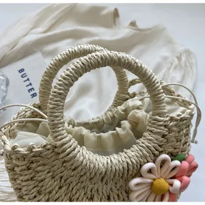 Detailed shot of woven straw bag featuring floral charm and drawstring inner lining