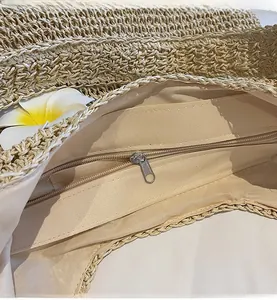 Detail of woven straw tote bag featuring smooth zipper closure and soft beige fabric lining