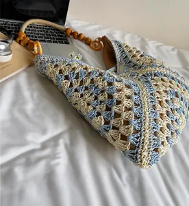 Detail of hand-woven straw bag with wooden bead strap and blue crochet patterns