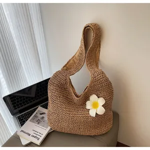 Detail of handwoven straw tote bag with a white frangipani flower and braided texture