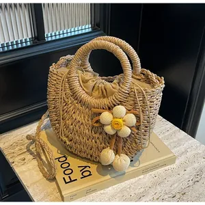 Detail of handmade straw half-moon bag with inner drawstring and knitted flower charm