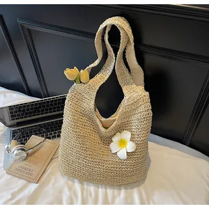 Detail of hand-woven straw hobo bag featuring a white frangipani flower and tulips