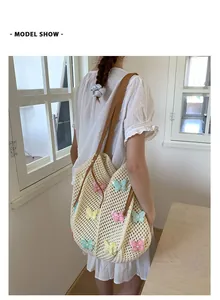 Détail du sac de plage tressé avec des patchs papillons colorés et des anses en cuir brun