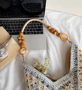 Detail view of hand-woven straw bag with dark wooden beads and blue textured patterns
