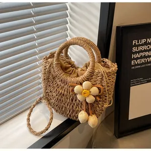 Detailed macro view of a semi-circular straw woven bag with crochet flower charm