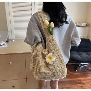 Rear view of a large straw shoulder bag with a white flower charm in a home office setting