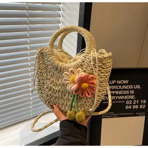 Detail of woven straw handbag featuring 3D floral pendants and secure drawstring closure