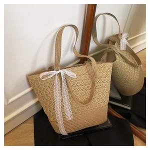 Detailed shot of woven straw tote bag featuring white lace bow and intricate openwork patterns