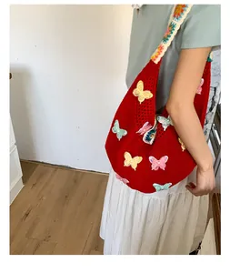 Detail der roten Stricktasche mit 3D-Schmetterlingsstickerei und Blumen-Häkelgurt