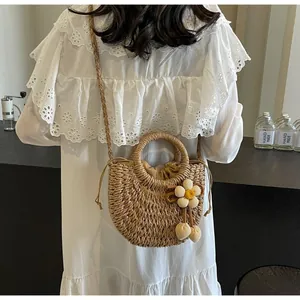 Rear view of a model wearing a semi-circular straw bag with a woven flower charm