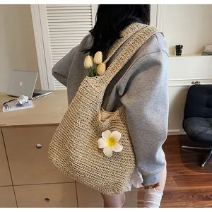 Detail view of large straw tote bag with woven texture and floral decorative accents