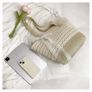 Close-up of woven straw tote bag with delicate white lace layers and a large bow detail
