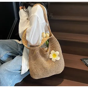 Detail of straw tote bag featuring a white flower charm and natural woven texture