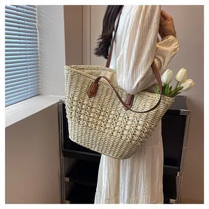 Close-up of woven straw tote bag with brown leather handles and hollow mesh texture