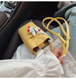 Detail van geel mini lederen telefoontasje met witte ganzenpatch in een auto-interieur