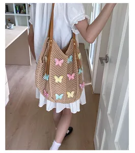 Détail des appliques papillons colorées sur un sac fourre-tout tissé kaki avec bandoulière
