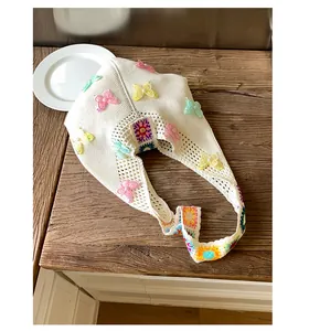 Detail der weißen Stricktasche mit 3D Schmetterlingen und floralem Häkelmuster