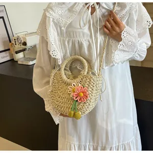 Detail of hand-woven straw bag featuring 3D floral accents and a drawstring closure