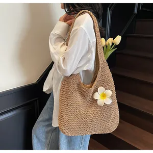 Detail of a beige straw hobo bag featuring a white floral ornament and inner fabric lining