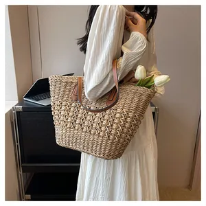 Detail view of woven straw tote bag with brown leather handles and interior space