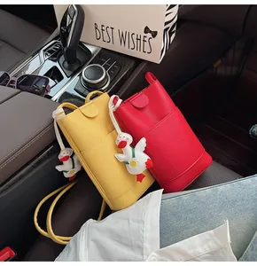 Detail van mini crossbody telefoontassen in rood en geel met schattige eendenhangers