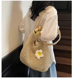 Detail of hand-woven straw tote with plumeria flower detail and comfortable shoulder strap