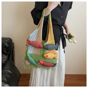 Detail of bohemian knit tote bag featuring colorful 3D fish dolls and green tassels