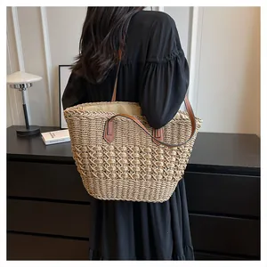 Detail of hand-woven straw tote bag with brown leather handles and hollow floral pattern