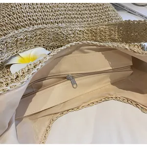 Detailed view of large straw tote interior with fabric lining and secure zipper pocket