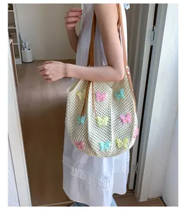 Détail du sac de plage au crochet avec papillons colorés et anses en cuir brun