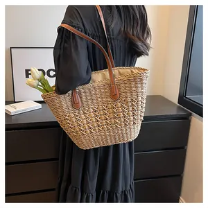 Detail of hand-woven straw tote bag featuring leather straps and hollow texture