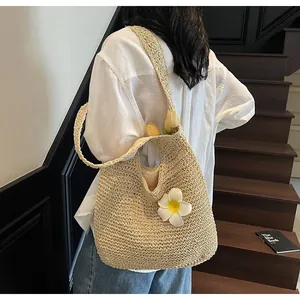 Detail of handwoven beige straw tote bag featuring a large white plumeria flower ornament