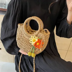 Detailed macro view of handmade straw bag with vibrant crochet flowers and drawstring closure