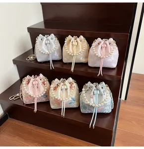 Detail view of jacquard bucket bags with pearl handles and floral silk embroidery