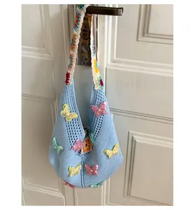Details der hellblauen Stricktasche mit Schmetterlingsstickerei und Perlenakzenten